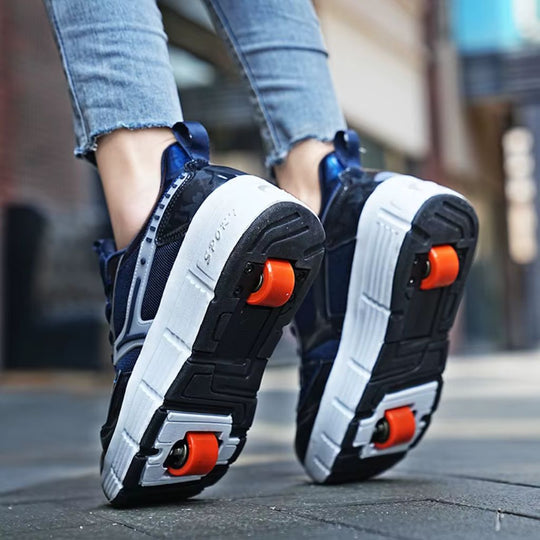 A close-up lifestyle shot of a person's feet wearing dark blue roller skate shoes with bright orange wheels, walking on a paved street