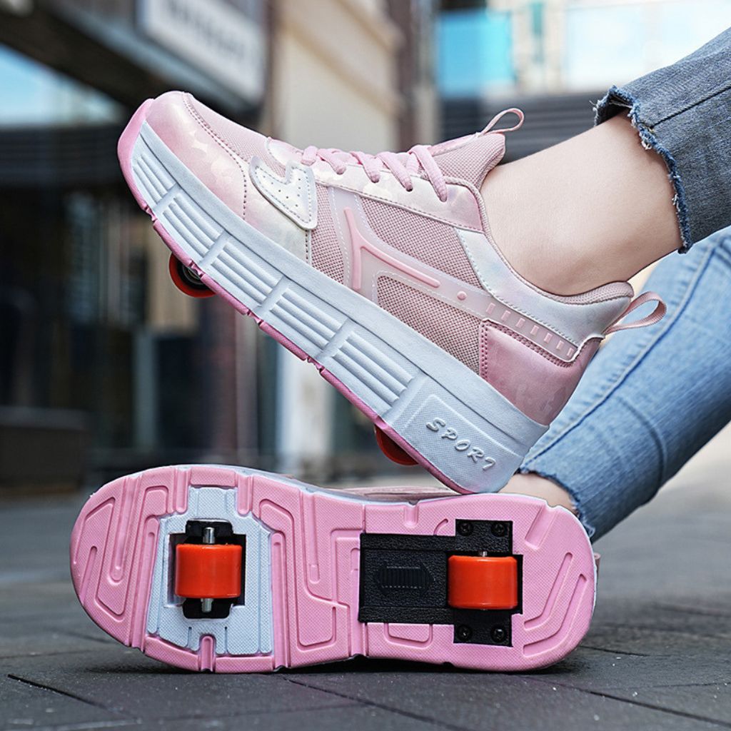 A pair of pink roller skate shoes with white and gray soles and wheel pads, shown on a person's feet with jeans in an outdoor urban setting