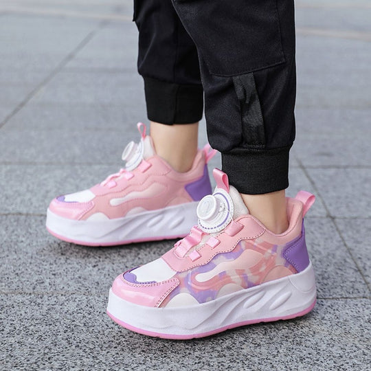 A person wearing pink chunky shoes with wheels, paired with black jogger pants, standing on a gray paved outdoor surface