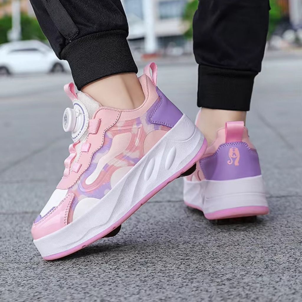 A pair of pink chunky roller shoes with detachable wheels with a dial-up twist lock closure, shown being worn on a person's feet on a gray asphalt street