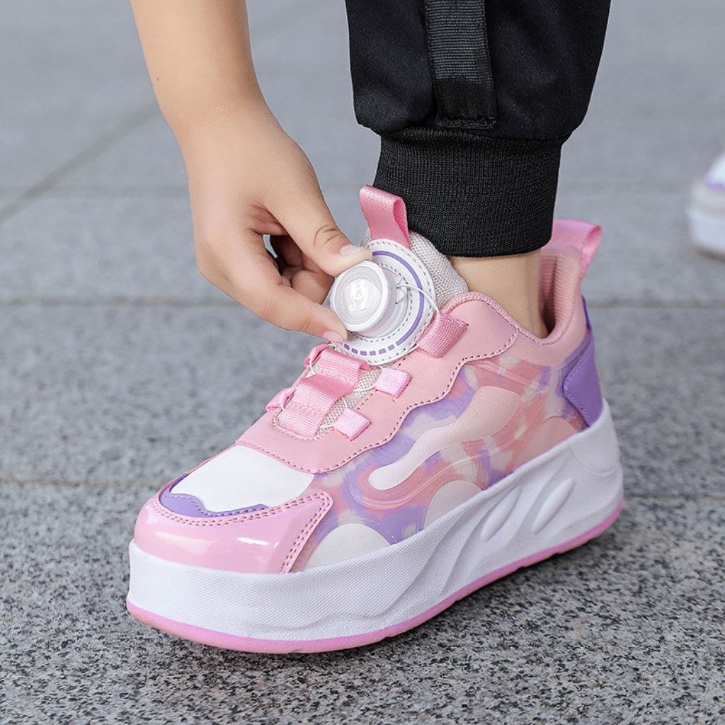 A girl wearing a pink sneaker with wheels, adjusts the dial closure on the the shoe, set against a gray pavement background
