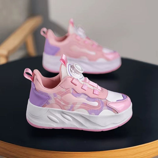 A pair of children's chunky roller shoes with heel wheels in pink, displayed on a dark round table